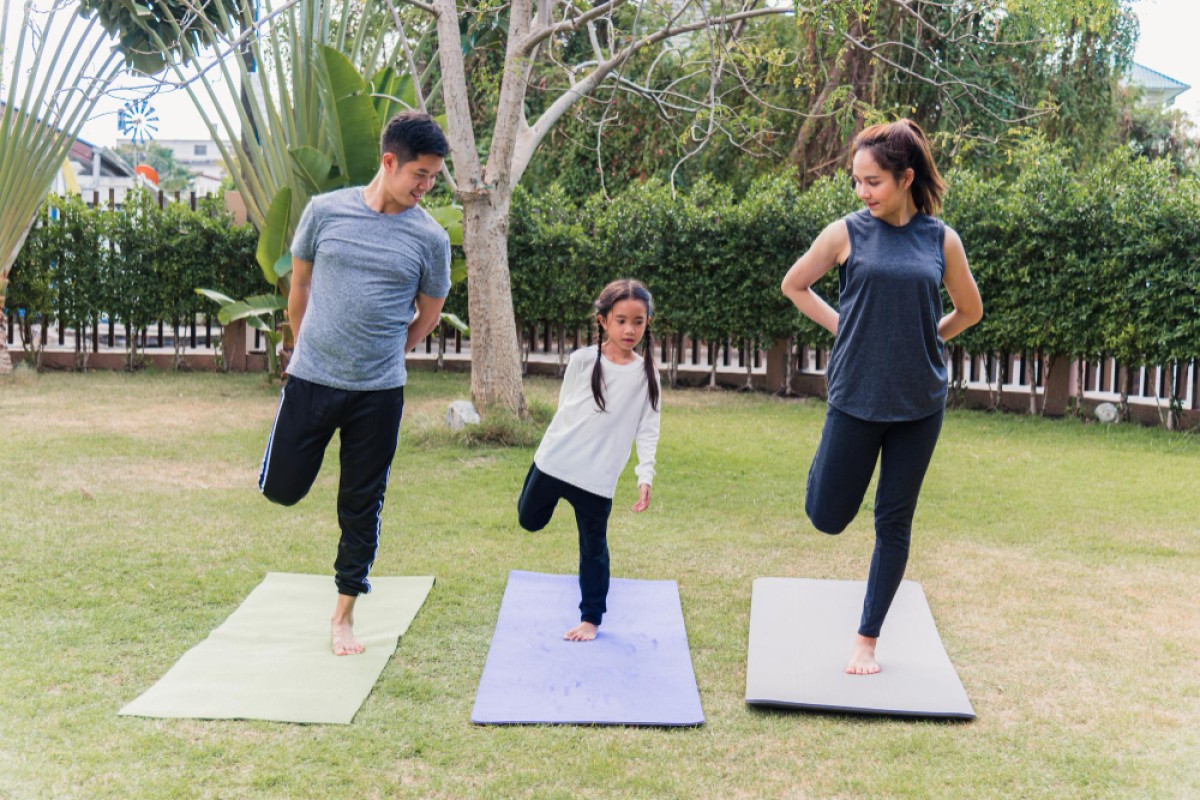 Father, daughter and mother doing yoga outdoors on yoga mats | Best CBSE School in Hyderabad